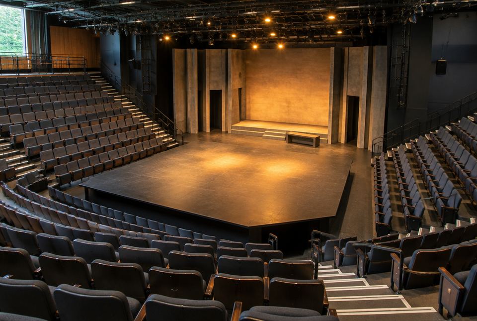 An empty theatre with a stage that reaches out into the seats on three sides.