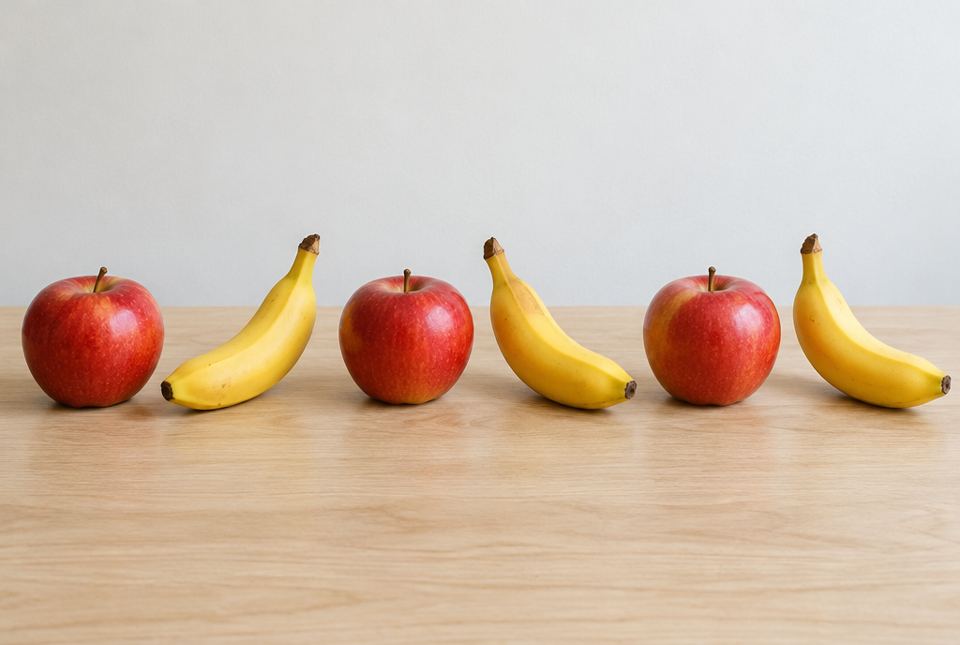 A row of real fruit on a table: apple, banana, apple, banana, apple, banana.